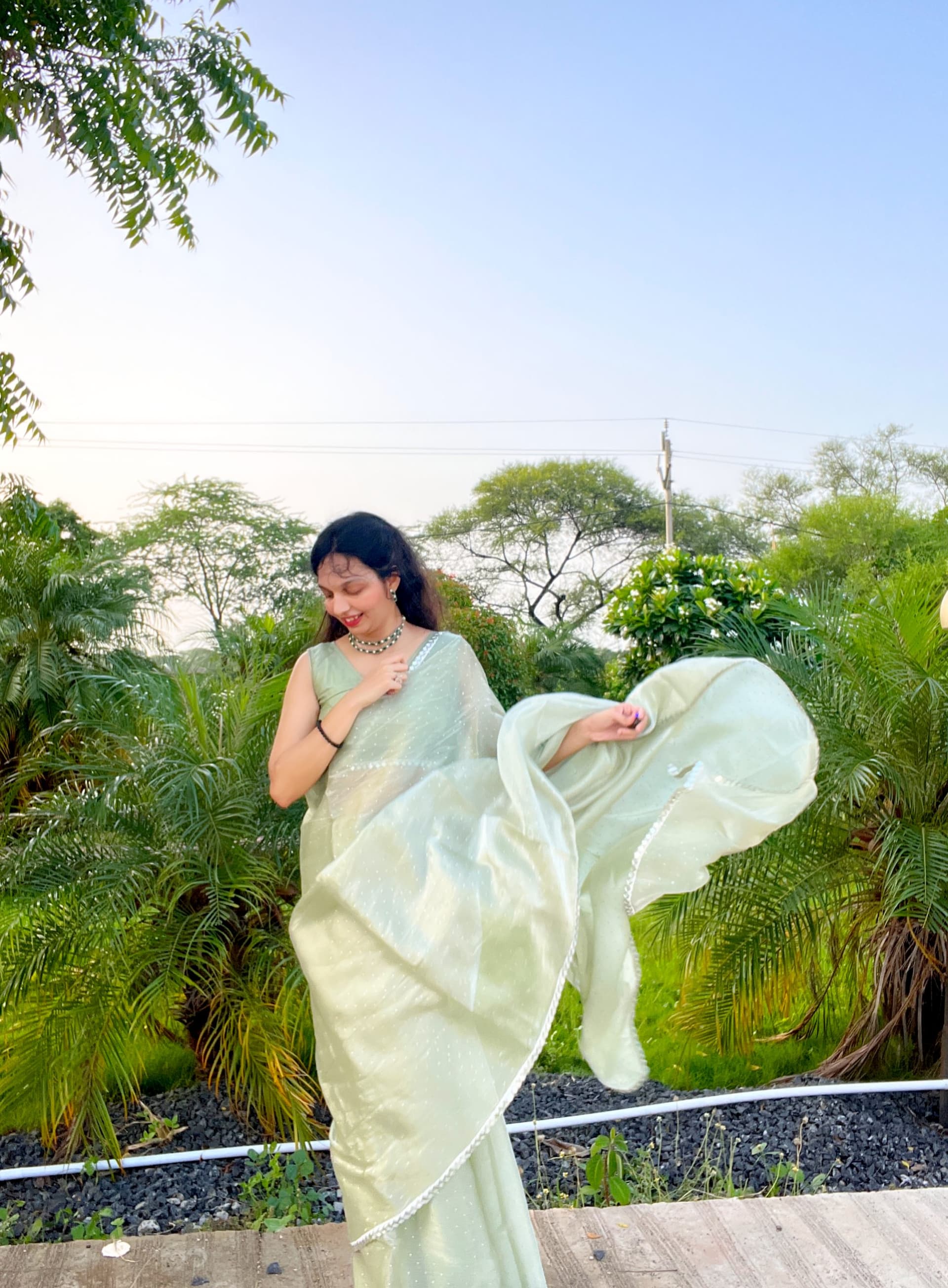 Ruchika Jharbade in a flowing mint-green organza saree, caught mid-twirl in a garden at dusk.